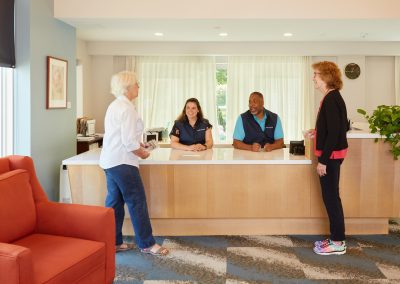 Staff and residents in friendly conversation at at Lasell Village luxury senior retirement community in Newton MA.